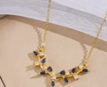 ByQueen | Κολιέ Sapphire Leaves με μπλε ζιργκόν πάνω σε διακοσμητική επιφάνεια